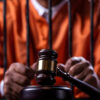 inmate behind bars with legal gavel in foreground