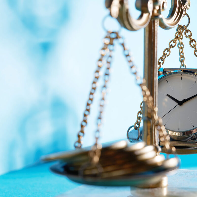 scales of justice with money on one side and clock on the other